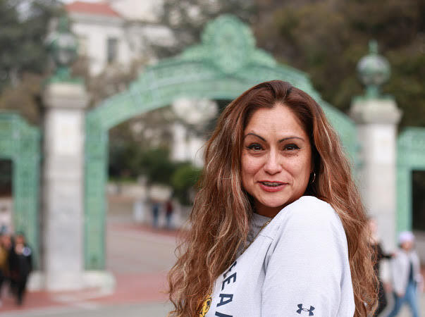 photo of a woman in front of sather gatre smiling for the photo in a white shirt